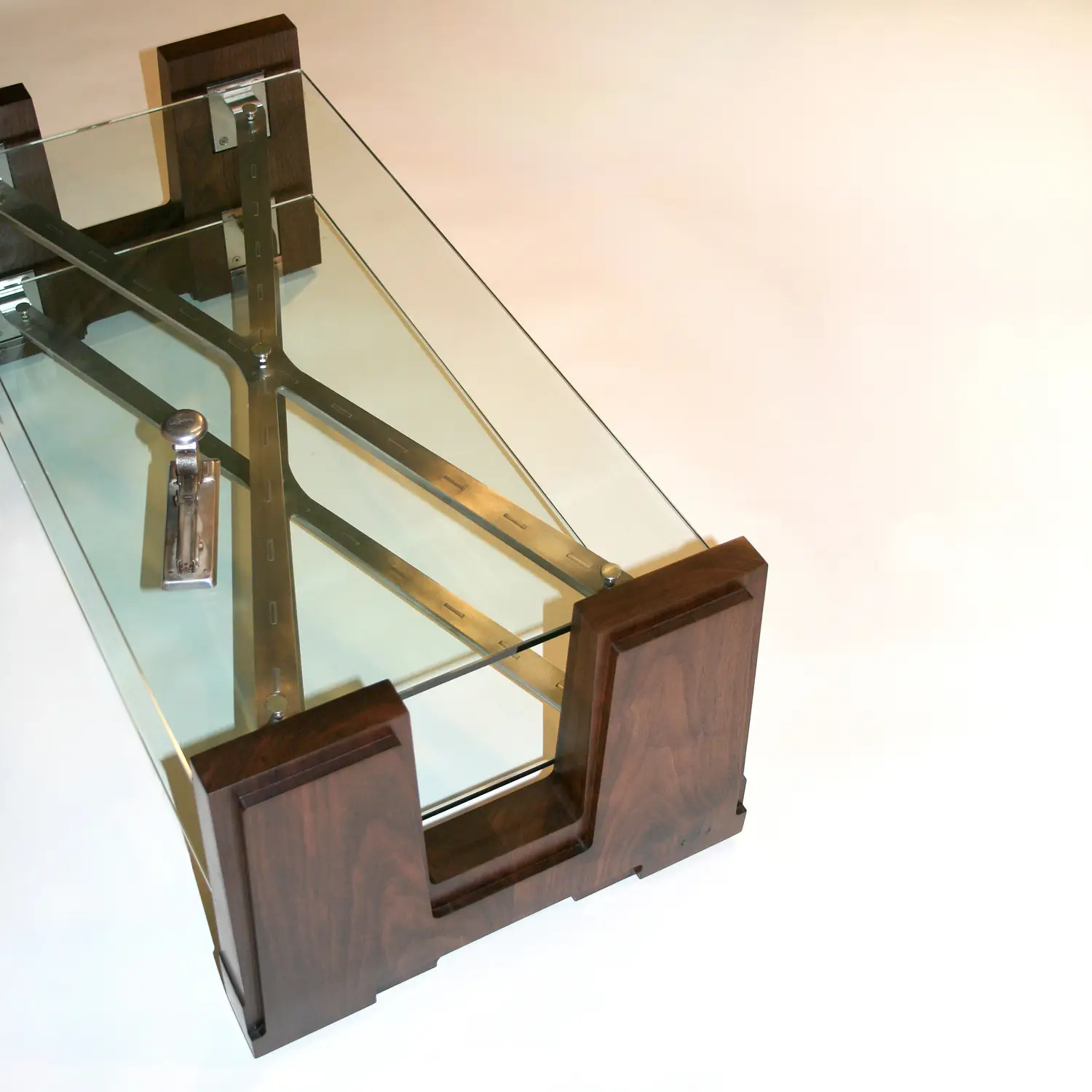 Extension Table with transparent glass surfaces supported by symmetrical wooden frames and steel connections.