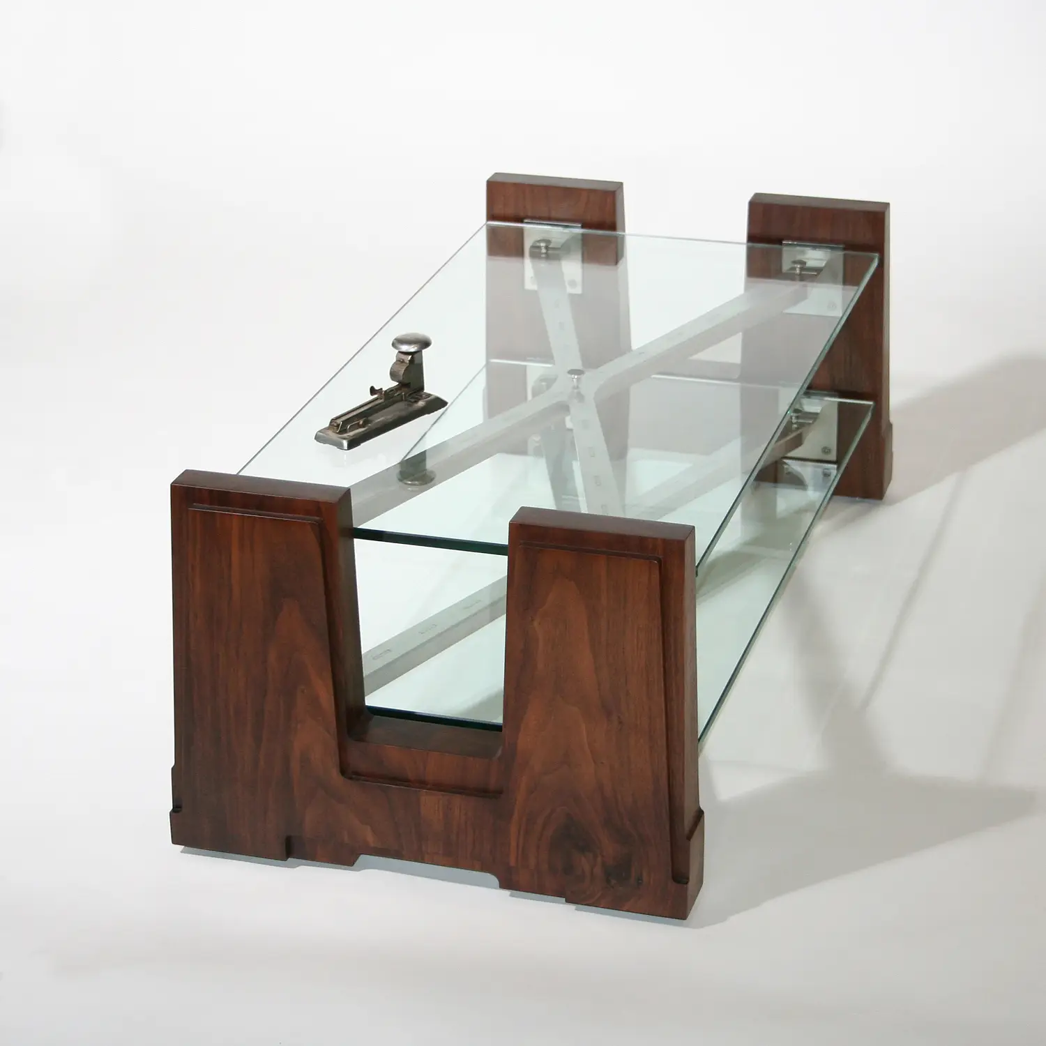 Front view of the Extension Table showing its glass tabletop and geometric wooden supporting structure.