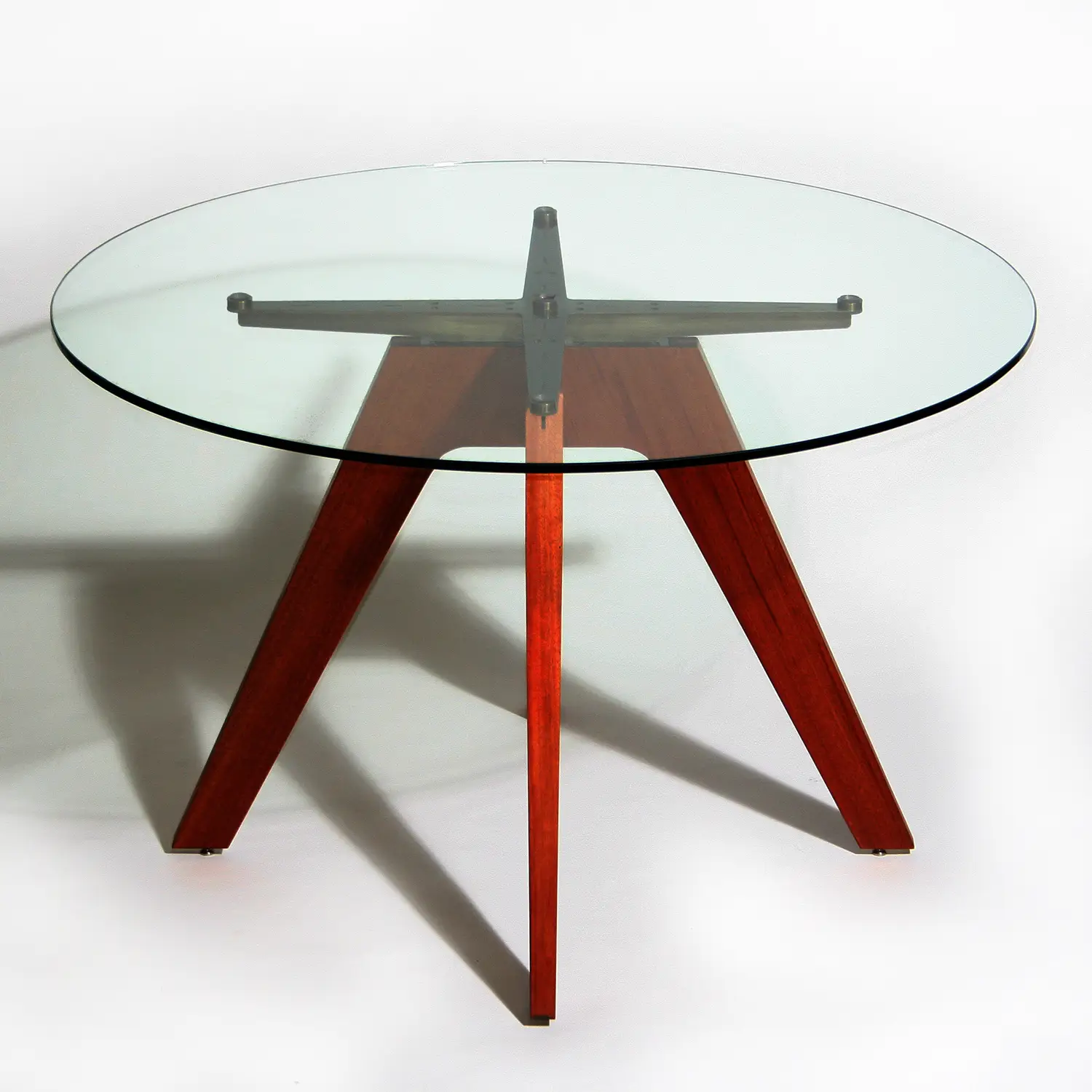 Float Table with a circular transparent glass tabletop supported by a sculptural wood and naval bronze base.