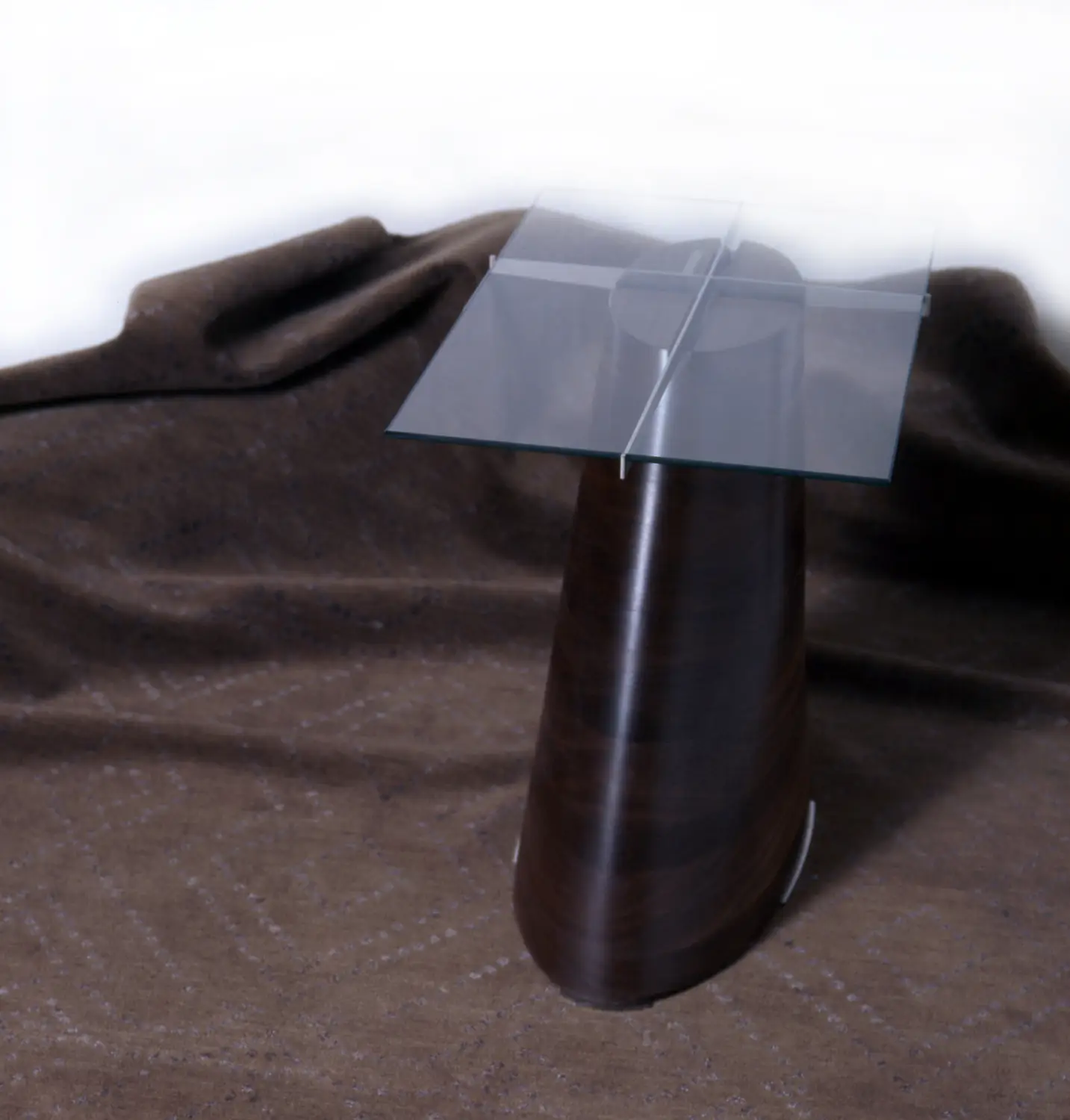 Side view of the Trunk Table against a fabric backdrop showing the contrast between wood and glass.