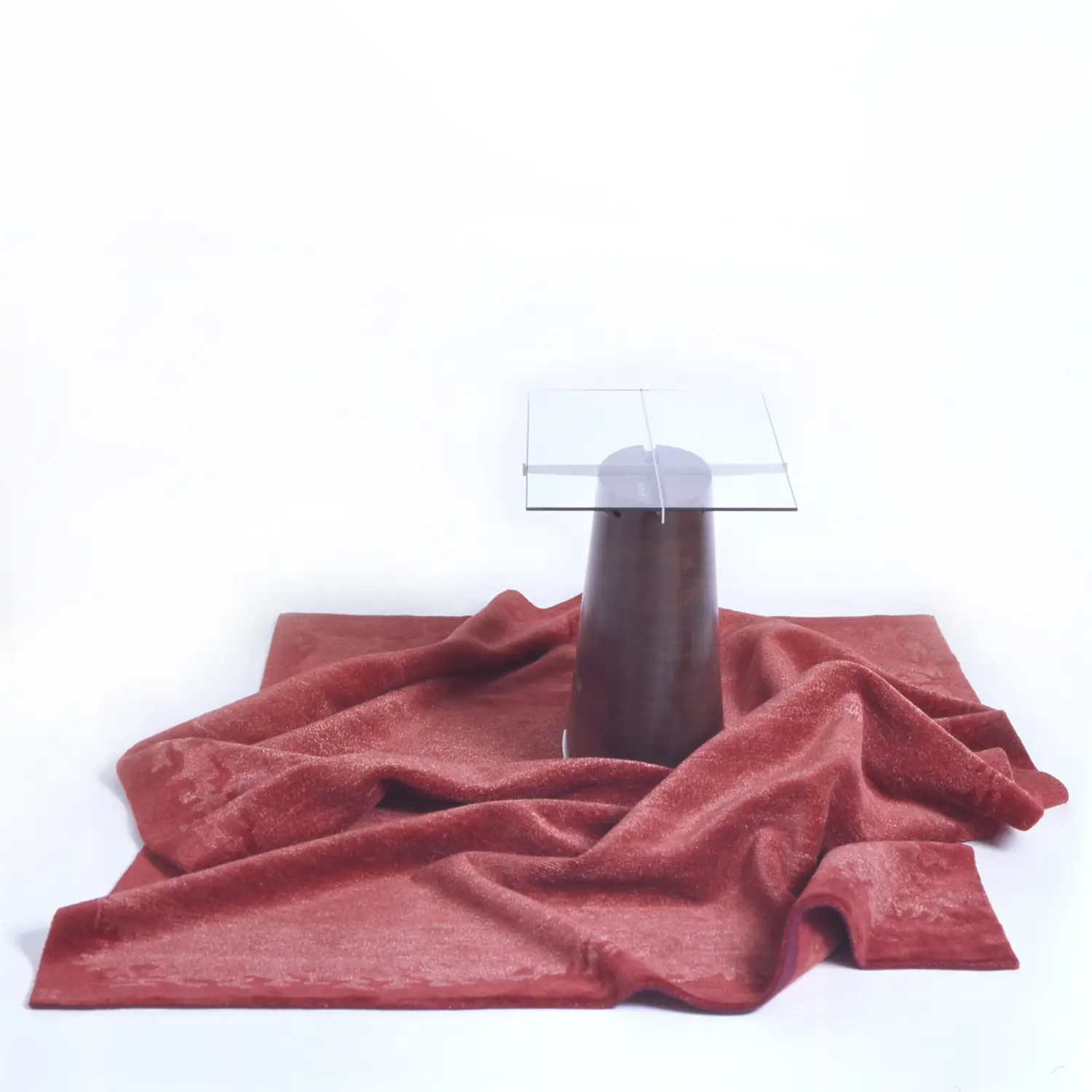 Trunk Table displayed with red draped fabric, emphasizing its sculptural form and transparent tabletop.